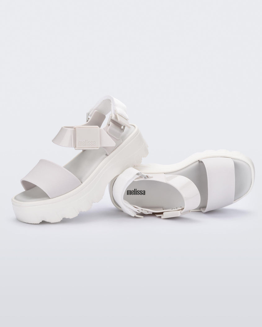 An angled top and side view of a pair of white Melissa platform Kick Off sandals with two straps.