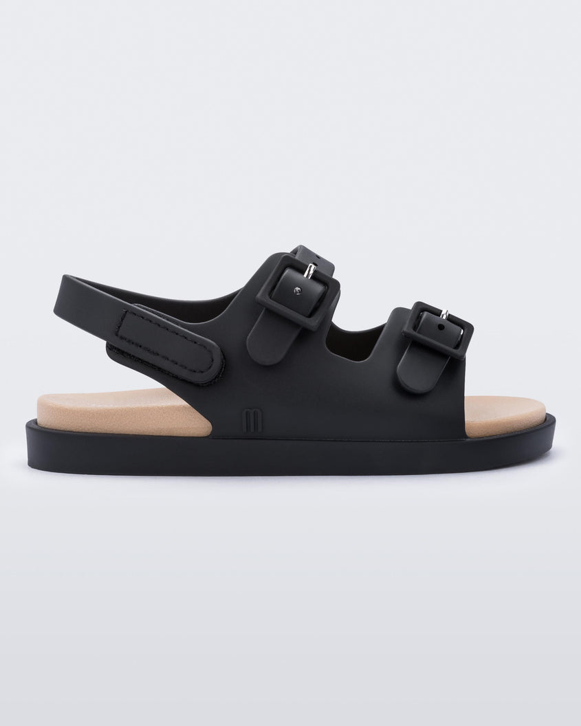 An outter side view of a black/beige Mini Melissa Wide Sandal with a black base, two black buckles at the top and a beige insole.