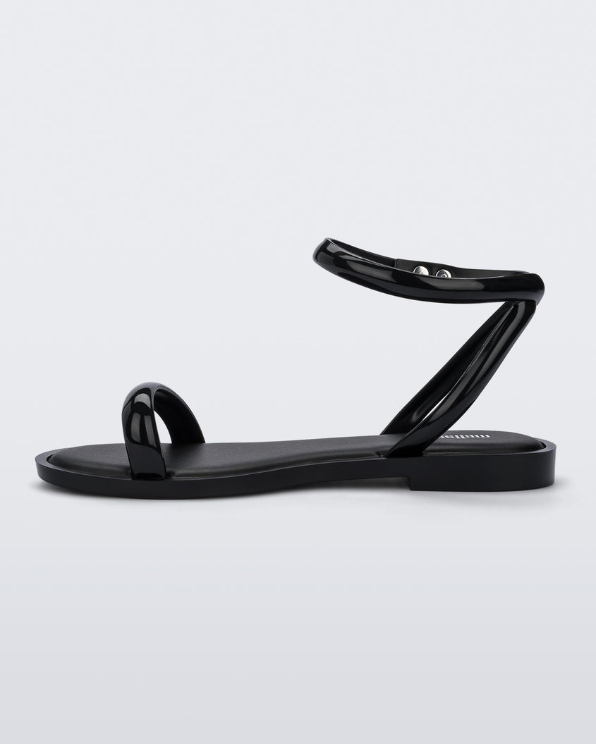 An inner side view of a black Melissa Wave Sandal with one front strap and one ankle strap.