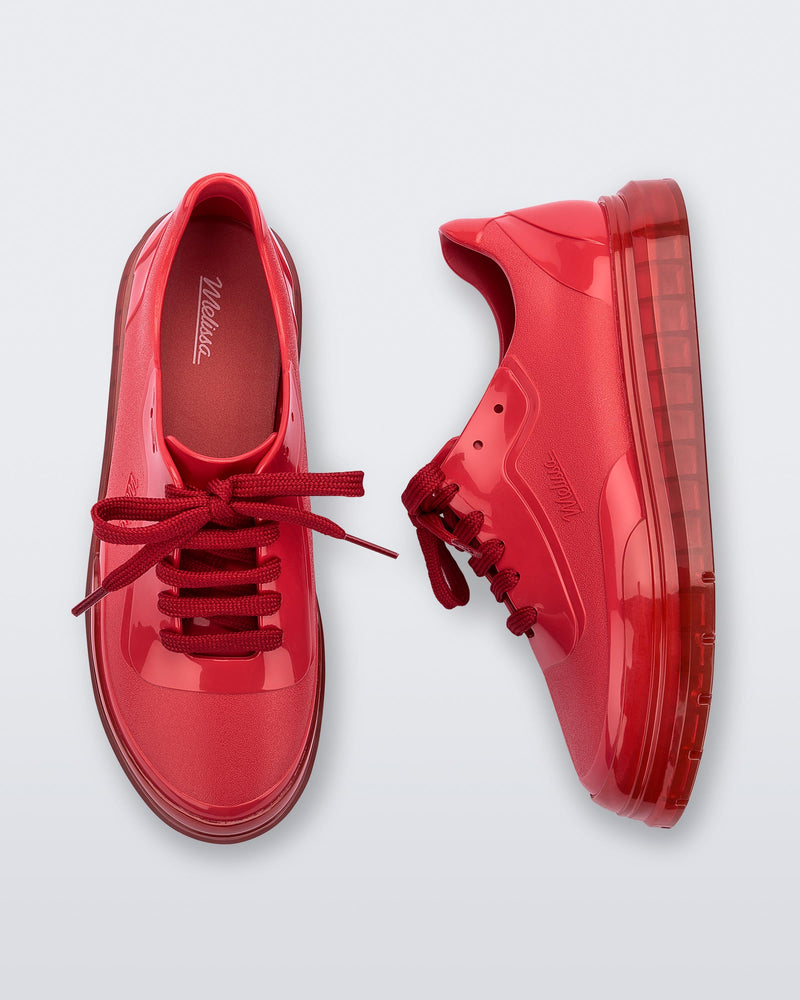 A top and side view of a pair of red Melissa Classic sneakers with a red base, laces, sole and a melissa logo on the side.