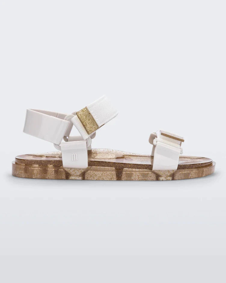 Side view of a Melissa Wide Papete sandal with gold glitter sole and white velcro straps
